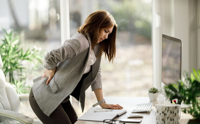 businesswoman bent over in pain - how to manage your low back pain