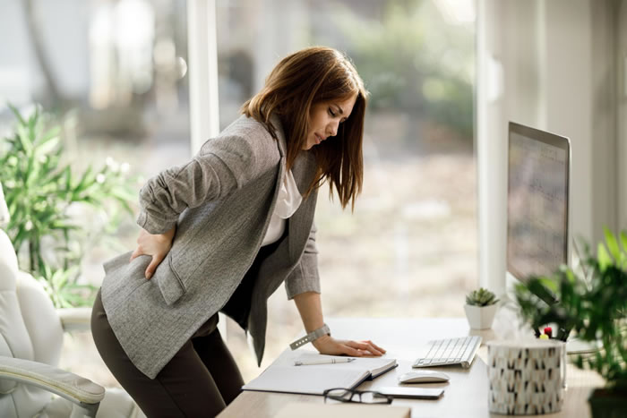 businesswoman bent over in pain - how to manage your low back pain